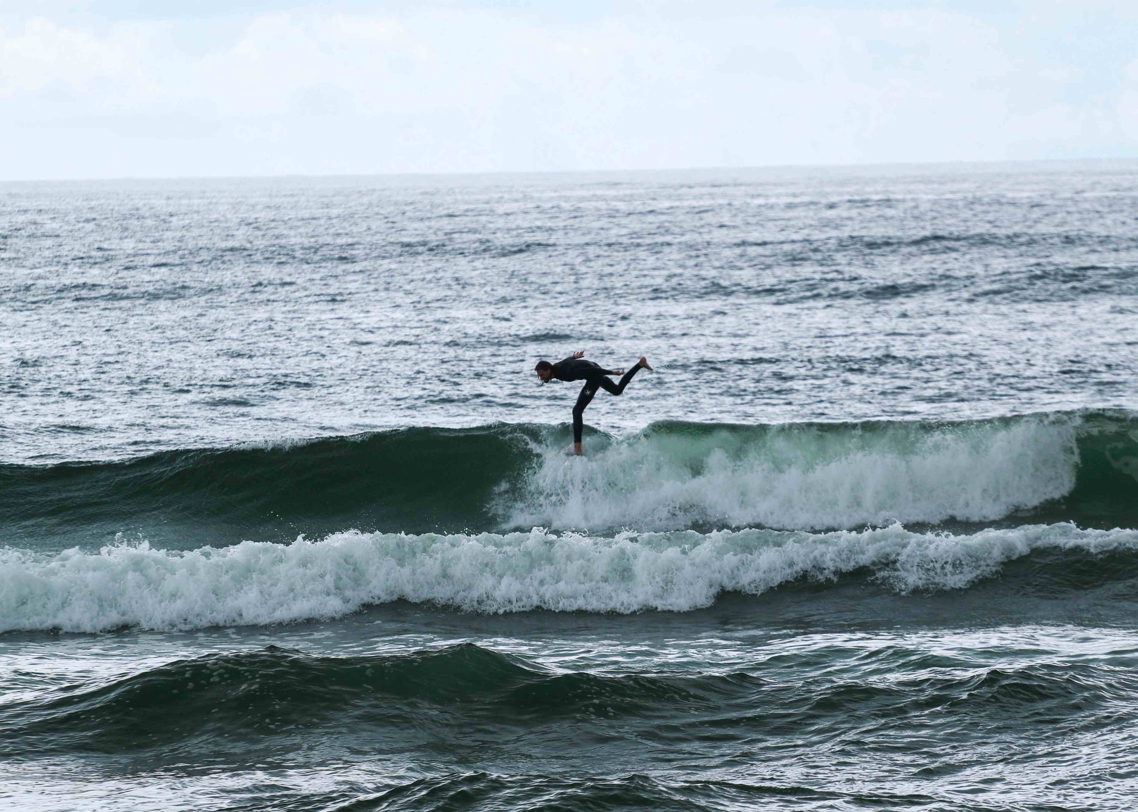 Surfer som står på brettet i bølgene.