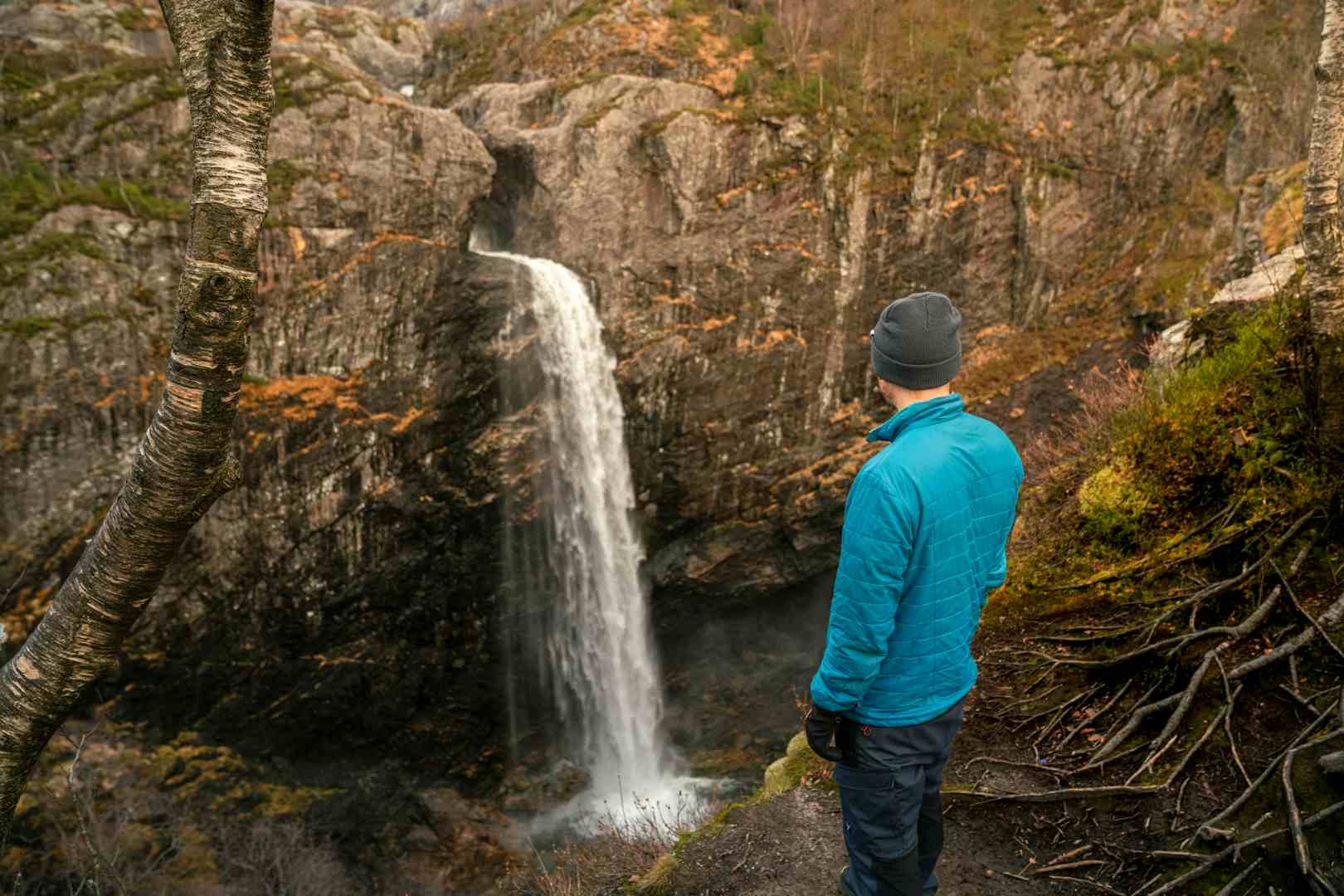 Man watching a waterfall in scenic surroundings in Norway