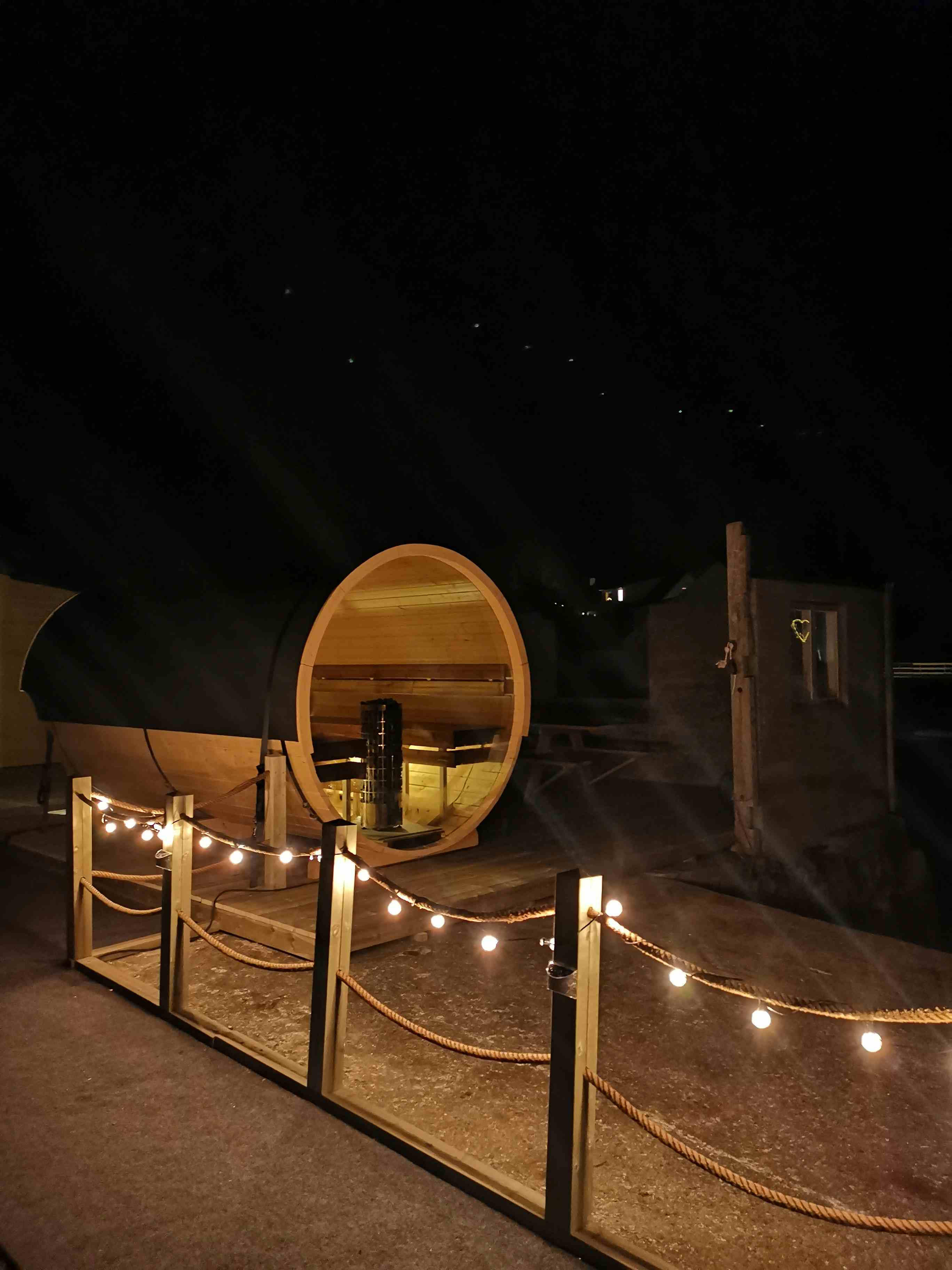 sauna, fire personer sitter inne i en tønne. det er mørkt ute, og måneskinn