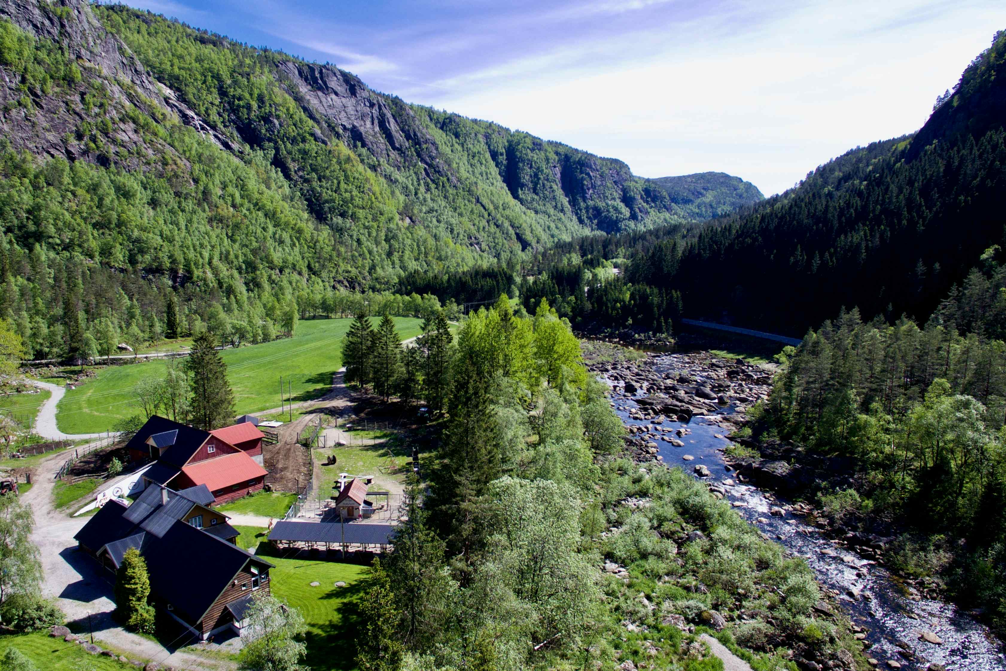 Bird's eye view of campsite at the Sirdal Huskyfarm. Mountains, valley and a river with camping buildings and campsite