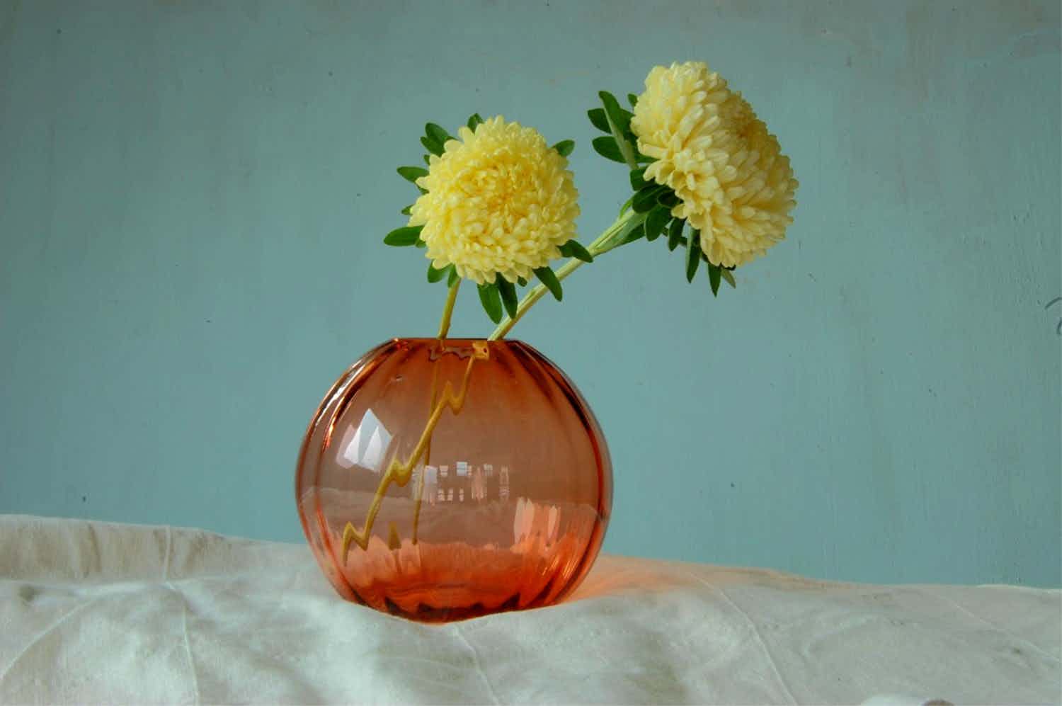 Tre vaser i glass i gul, grønn og oransje med snøklokker i.