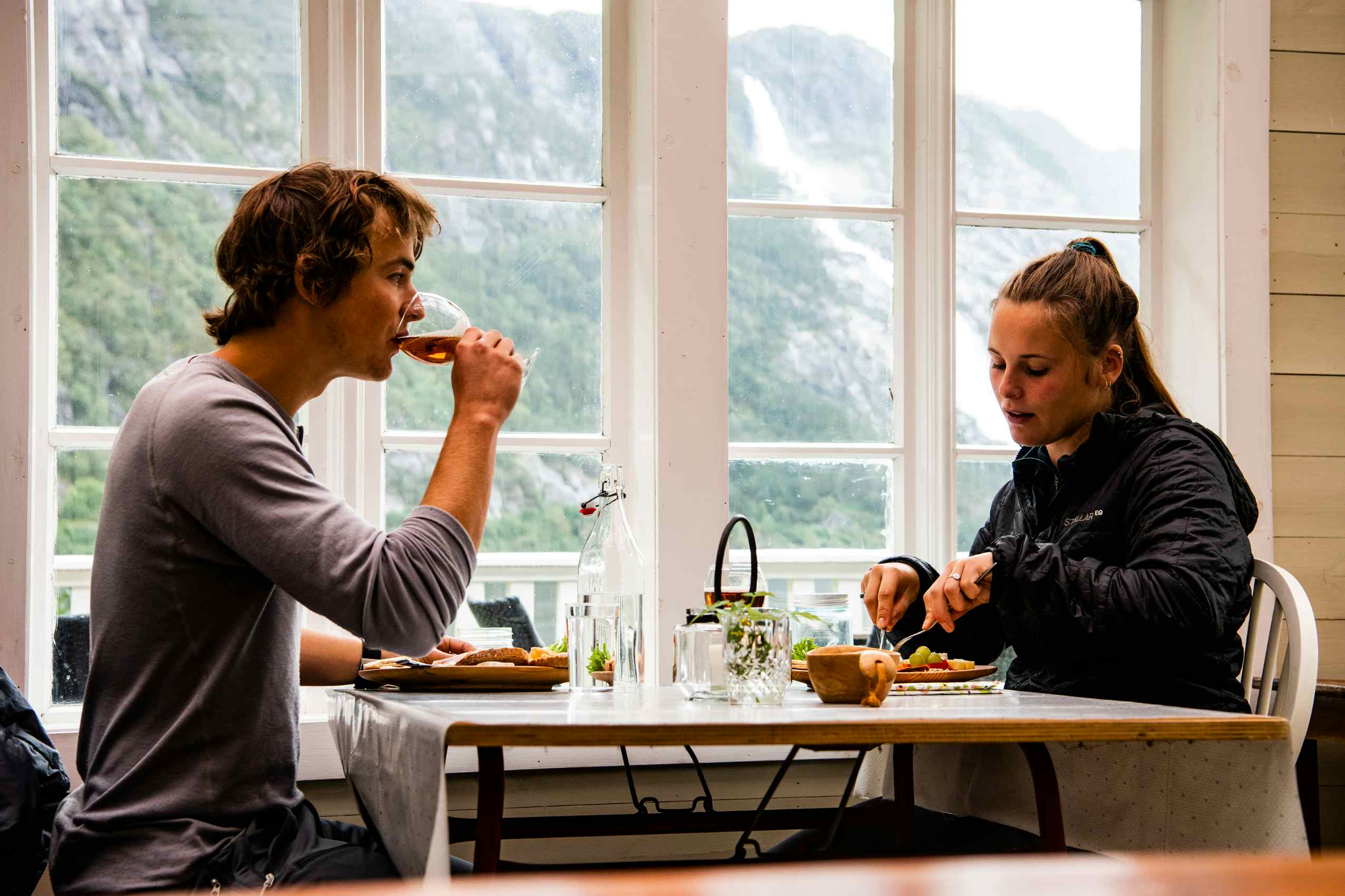 Et ungt par som spiser lunsj på Eljarvik gard med Langfoss i bakgrunnen