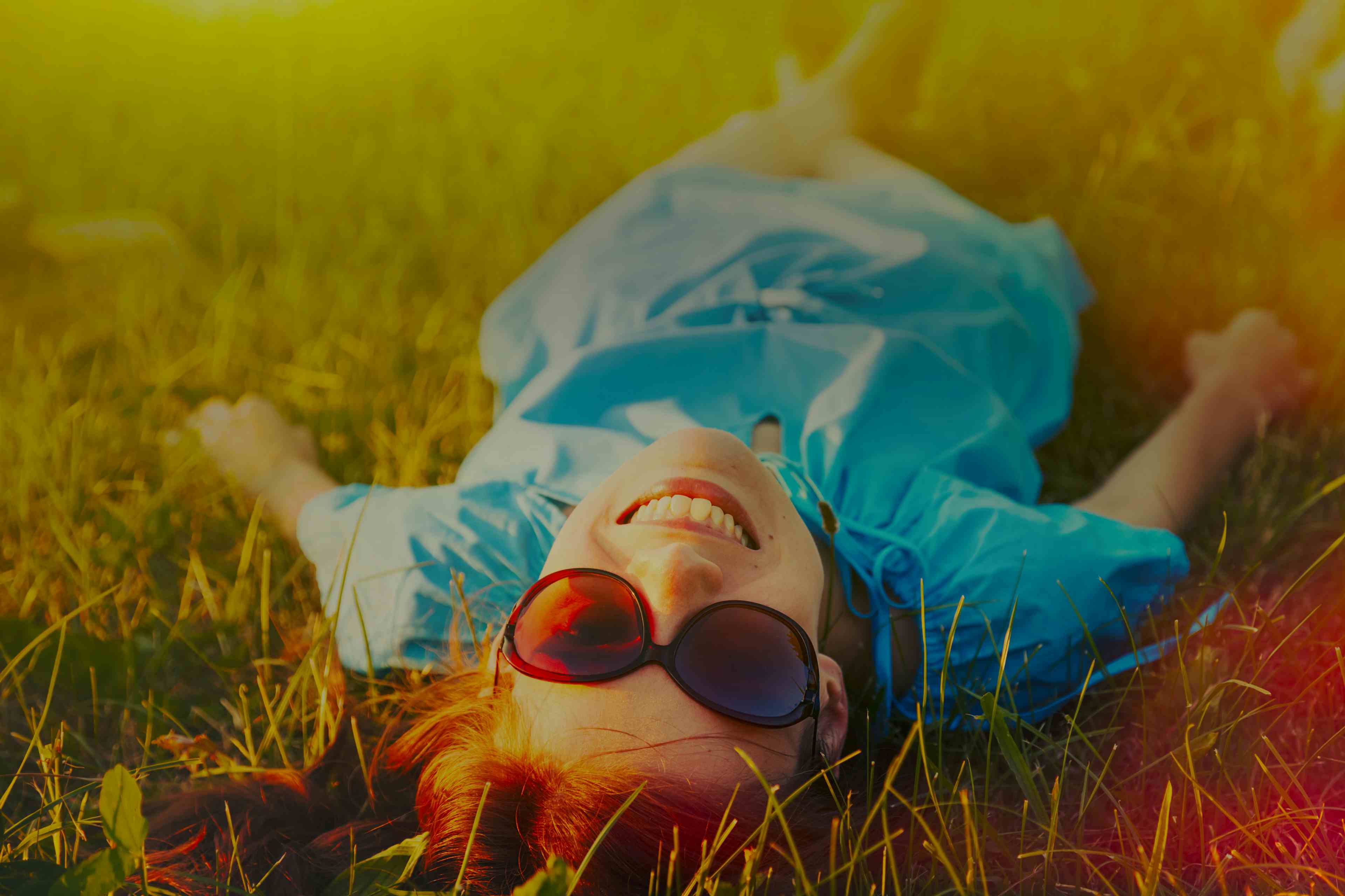 Glad person ligger i gresset og gjør ingenting