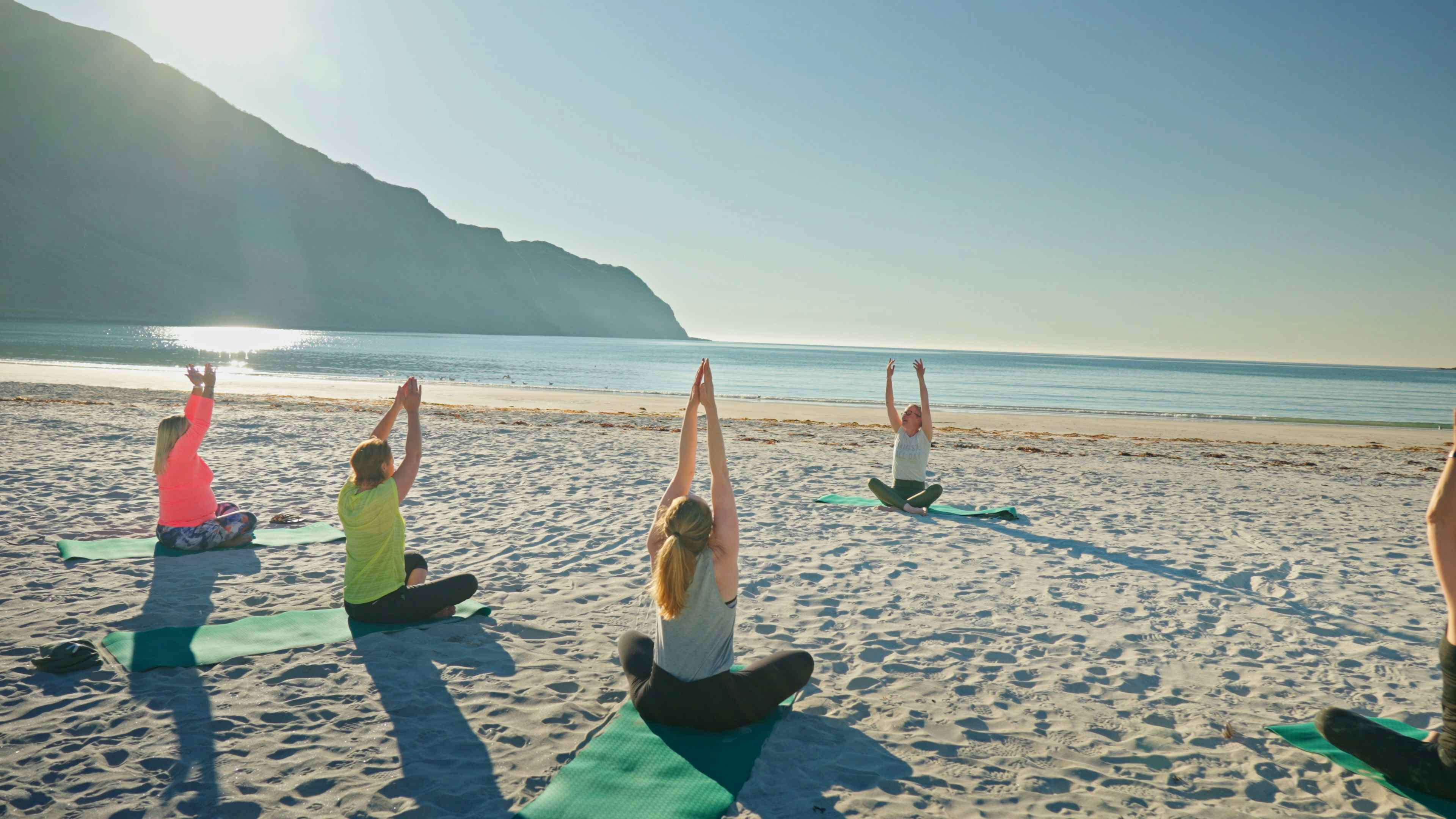 Gruppe mennesker gjør Yoga på Refsviksanden i deilig sollys