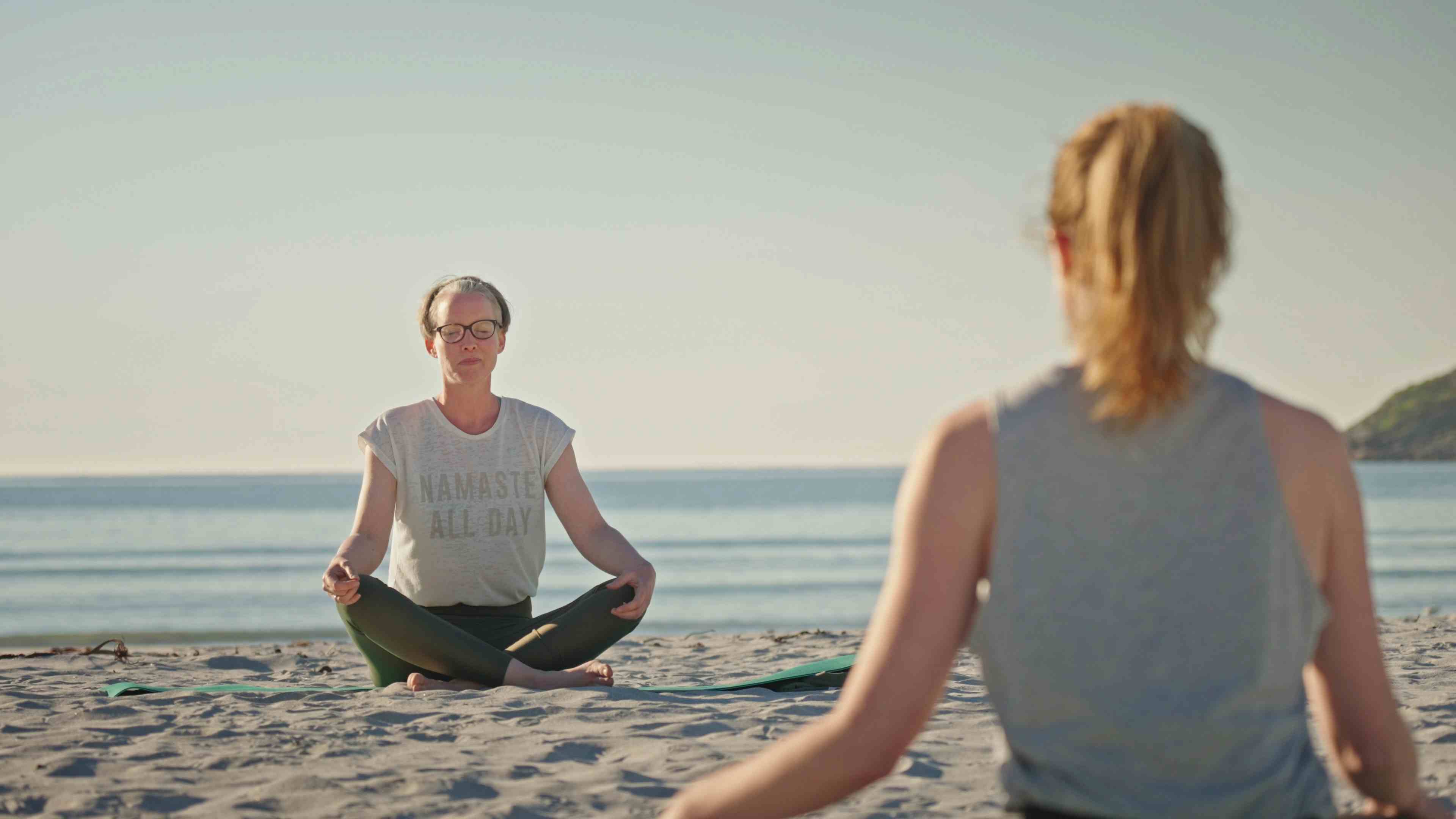 Gruppe mennesker gjør Yoga på Refsviksanden i deilig sollys