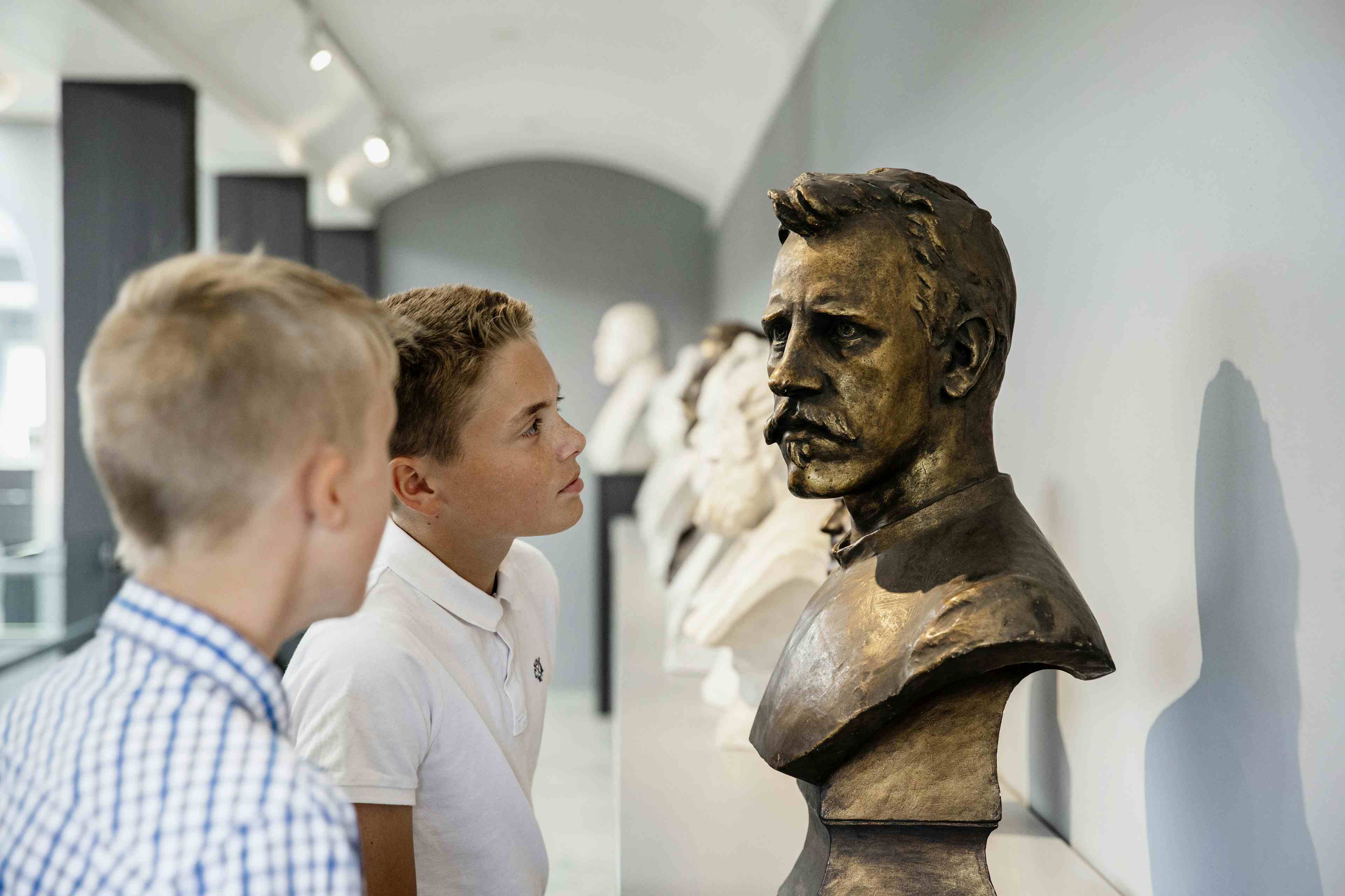 Gutar studerer ei byste av person på Anders Svor-museet.