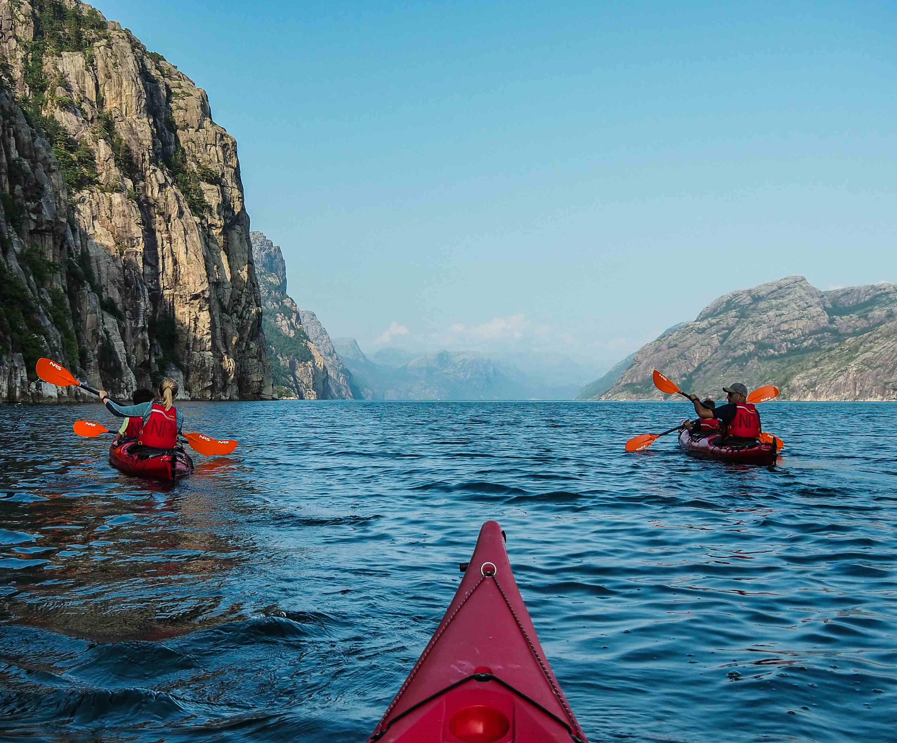 Tow people kayaking in the blue Lysefjord with mountains on each side