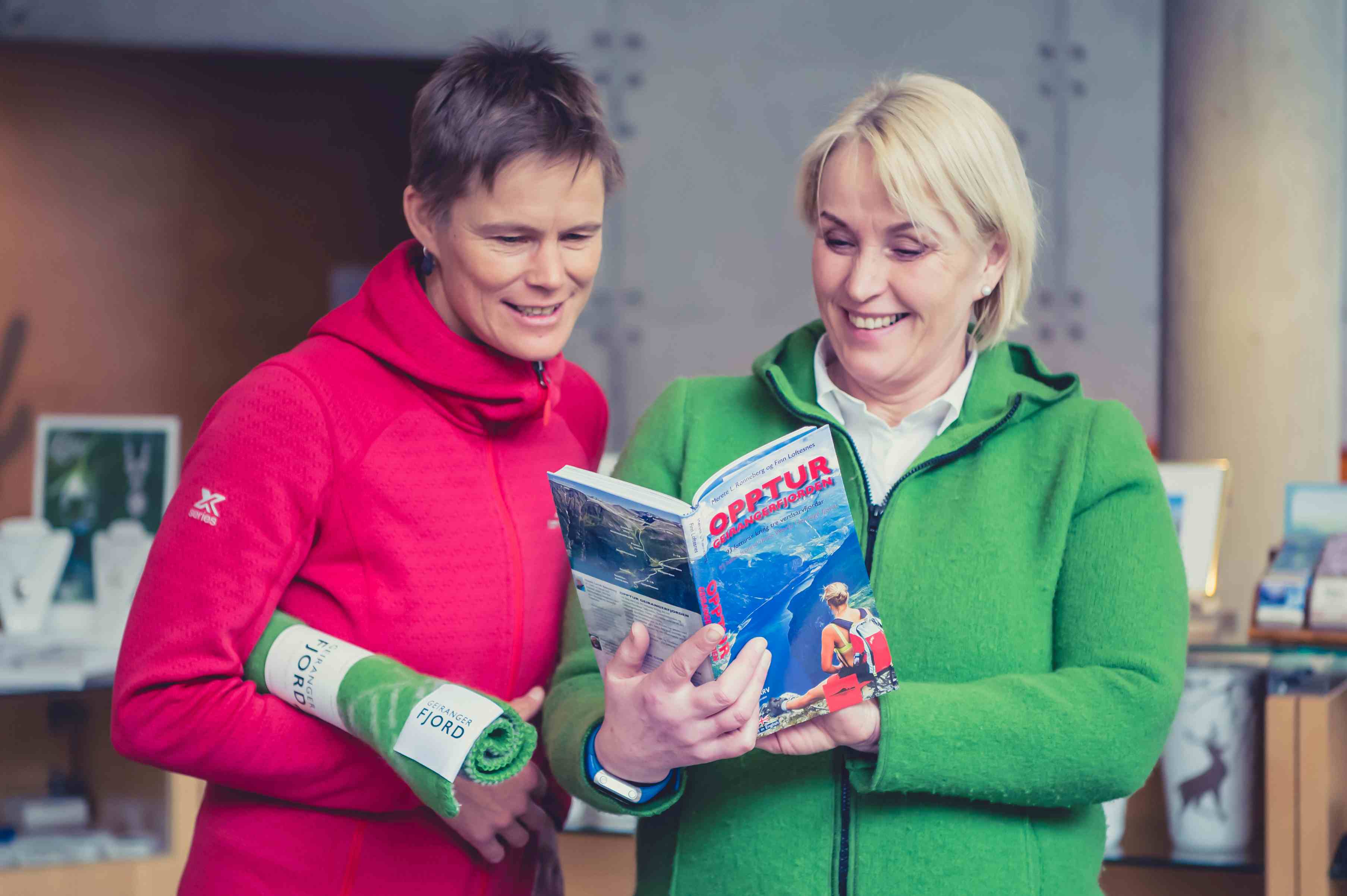 Damer leser i en bok i Norsk Fjordsenter sin butikk