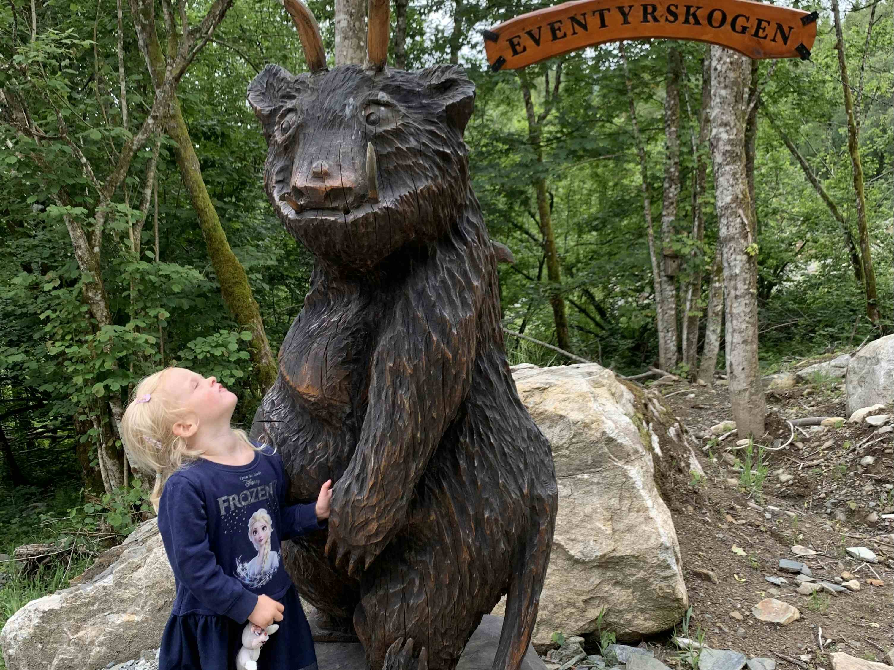 En jente som kikker på en stor, utskåret bjørn med horn.