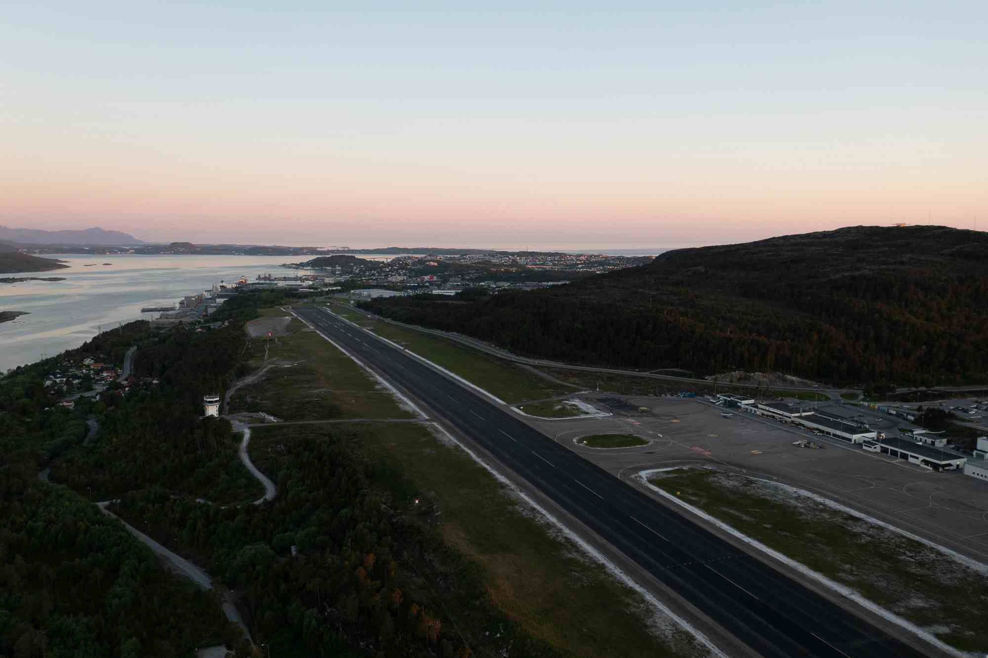 Dronebilde med utsikt over flyplass mot Tustnafjellene i solnedgang