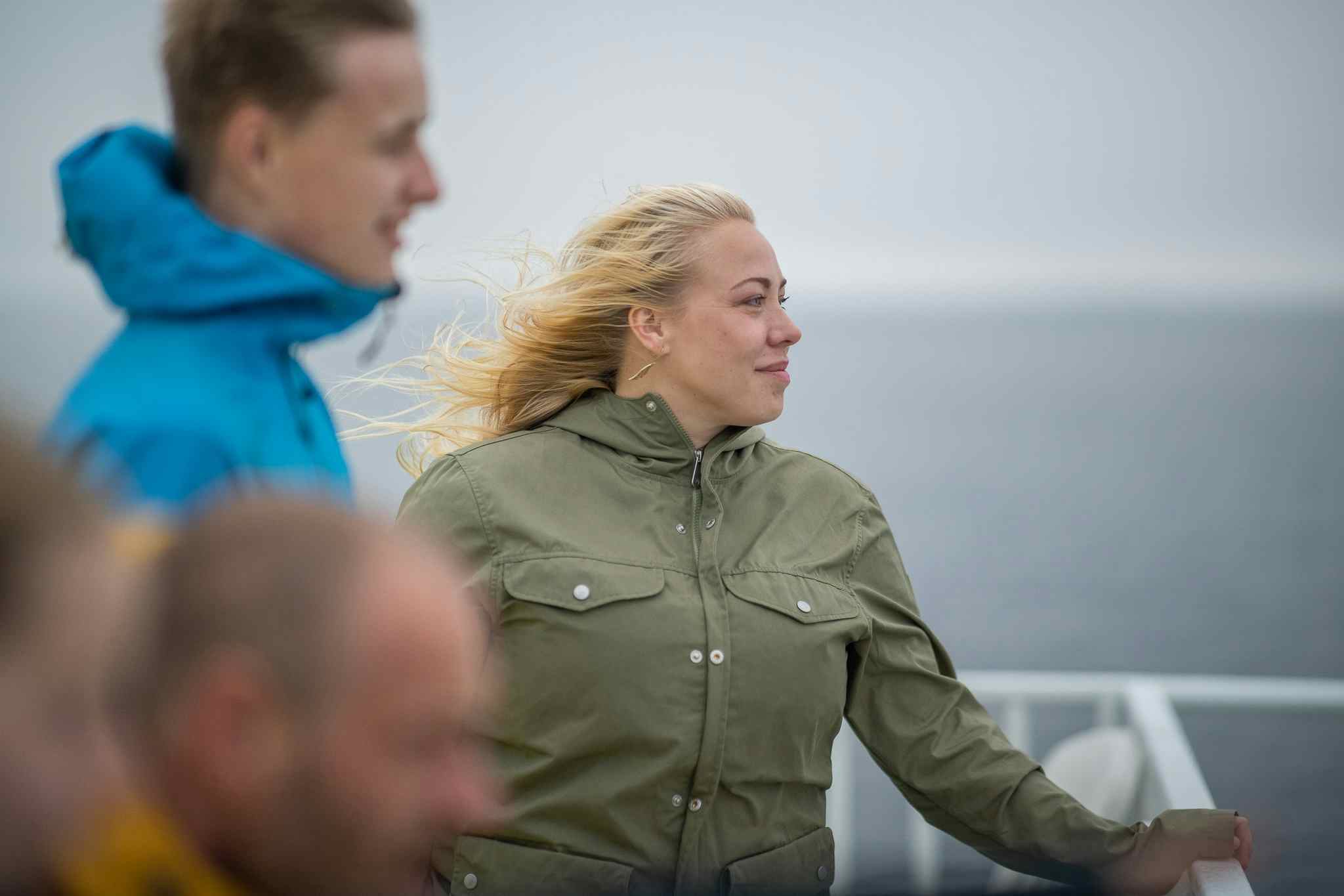 Group of people on a ferry. Standing on deck with the wind in their hair