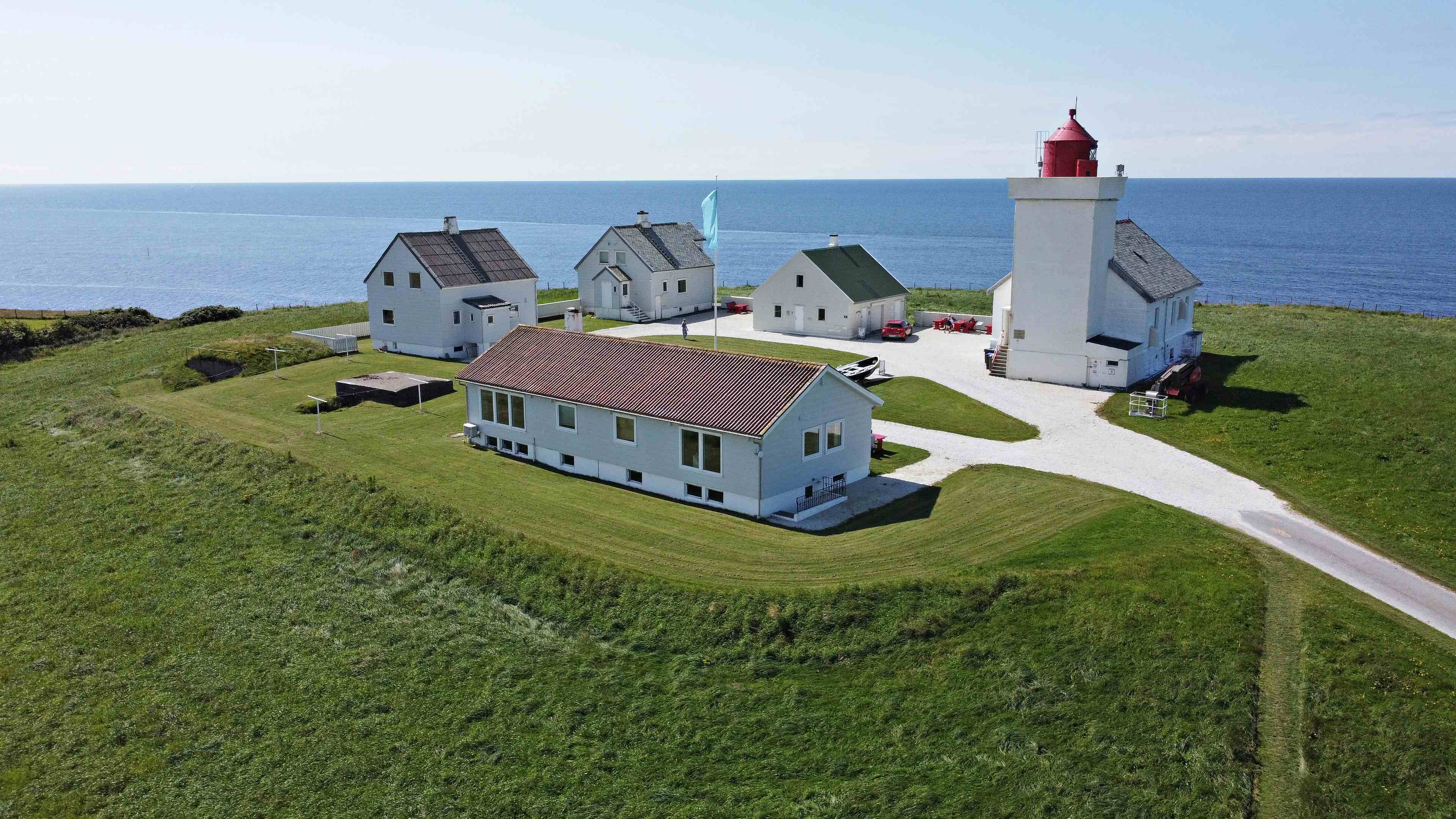 Obrestad lighthouse with all buildings taken from above. The sea and green fields surrounding the lighthouse.