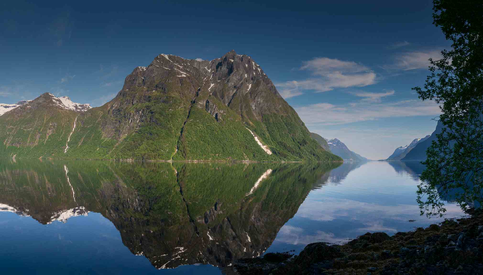 Fra Sæbø ser man til  Sæbøneset, og høge taggete fjell i bakgrunnen.