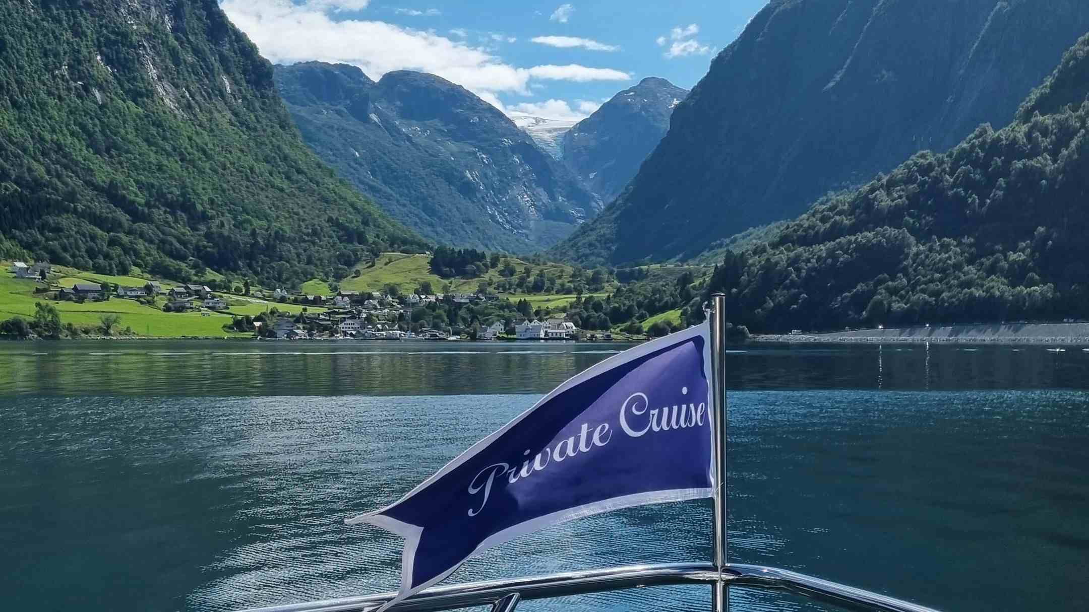 The flag of the behind of the boat facing picturesque fjord landscapes