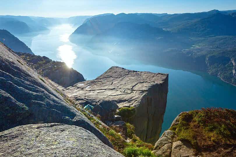 Preikestolen mountain plateau seen from above. Surrounded by a blue fjord and mountains on each side of the fjord.