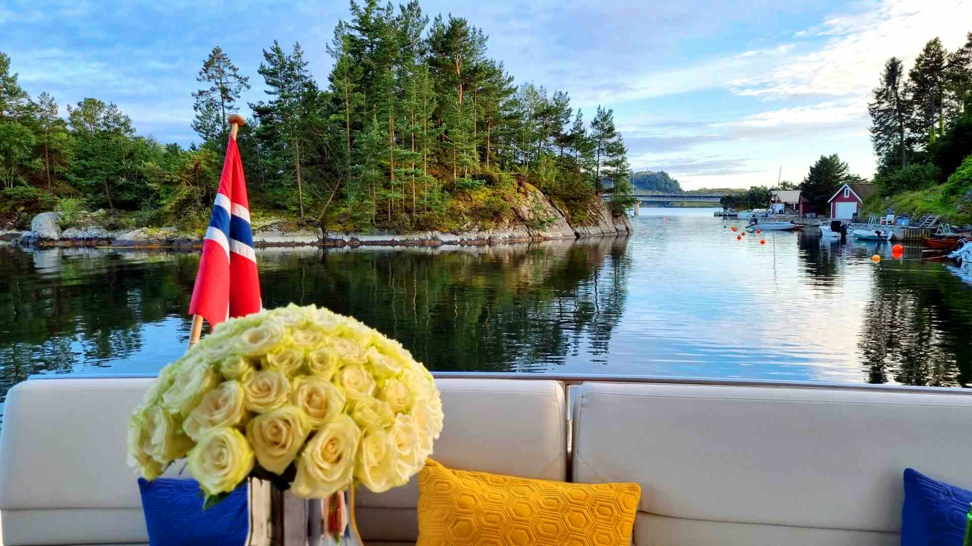 Two people sitting on deck of the boat at a yacht cruise with Private Cruise to the city islands of Stavanger. Blue skies and island scenery