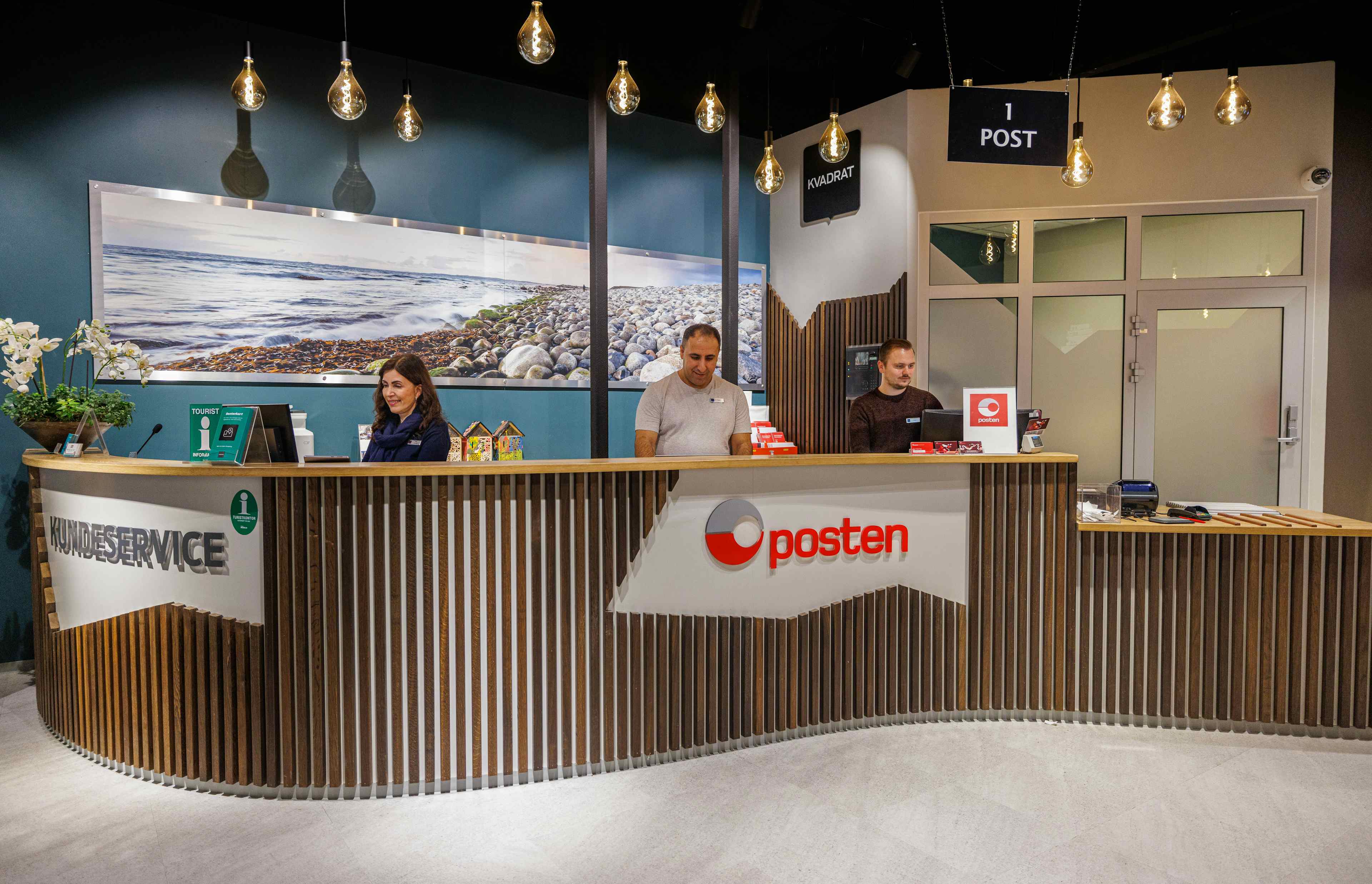 three people sitting at the counter of the tourist information at the kvadrat shopping centre with shops