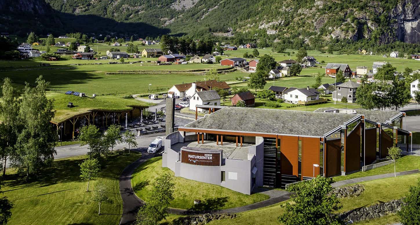 Et dronebilde av Norsk Natursenter med hus og gårder i bakgrunnen.