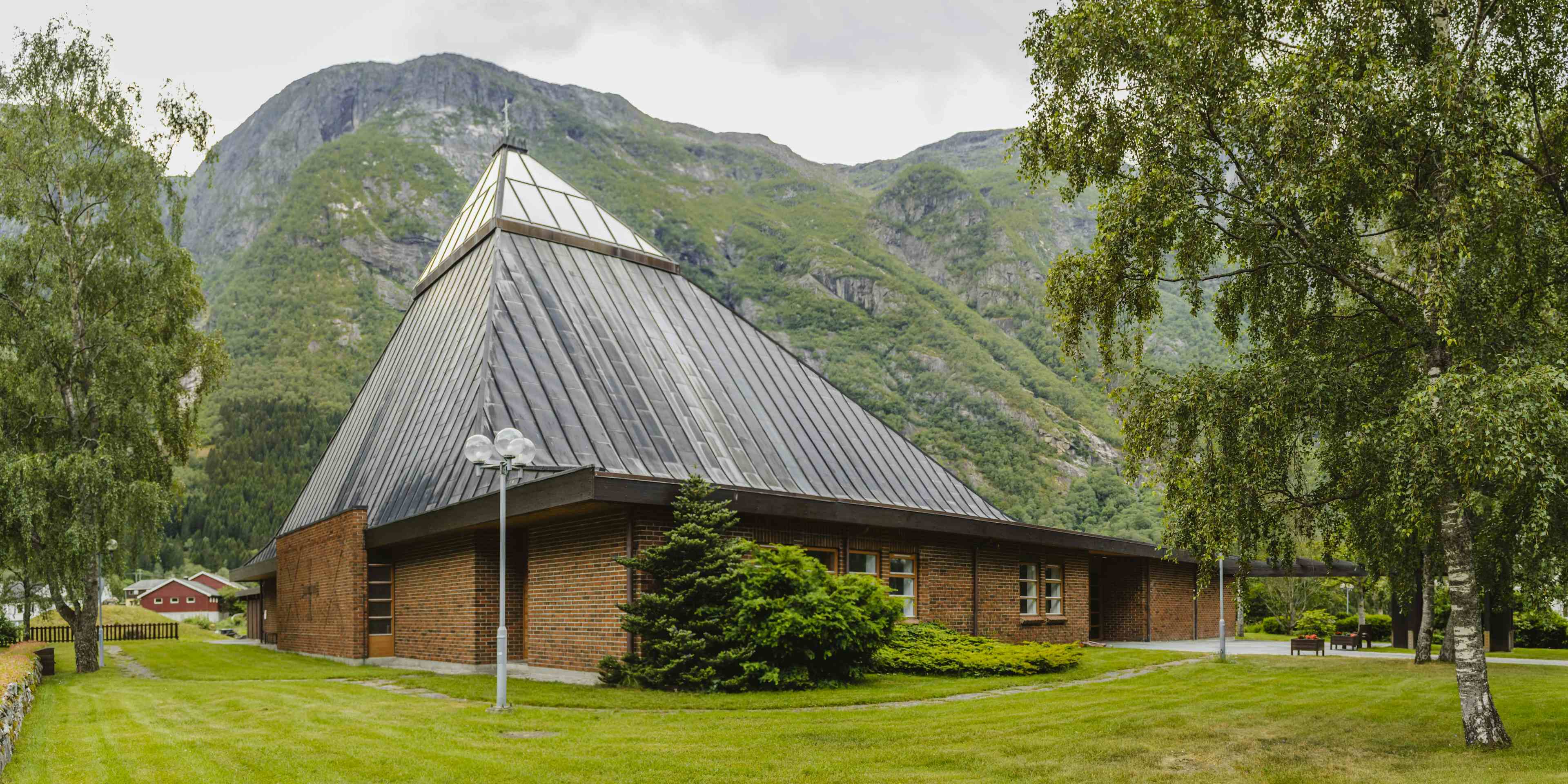 Eidfjord nye kirke sett fra utsiden. Den er laget av rød murstein med en trekantet glasstak.