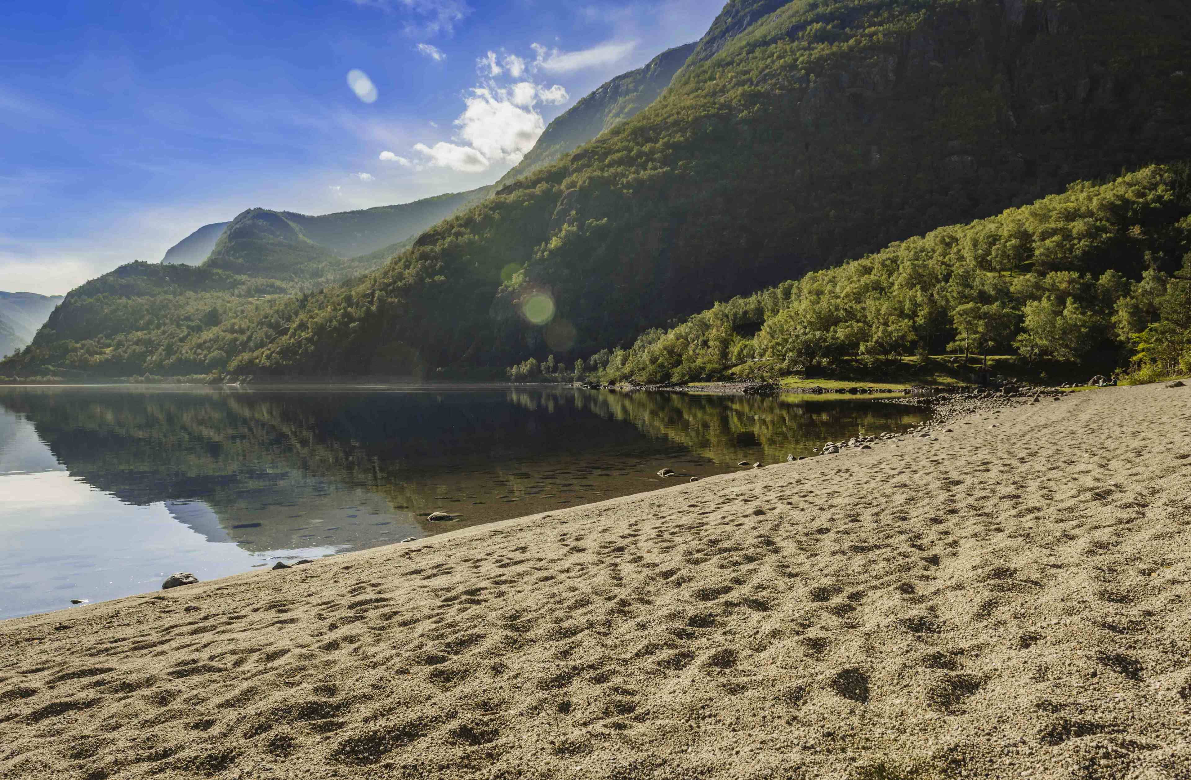 Sandstranda ved Eidfjordvatnet. Fjellene rundt innsjøen reflekteres perfekt i innsjøen.
