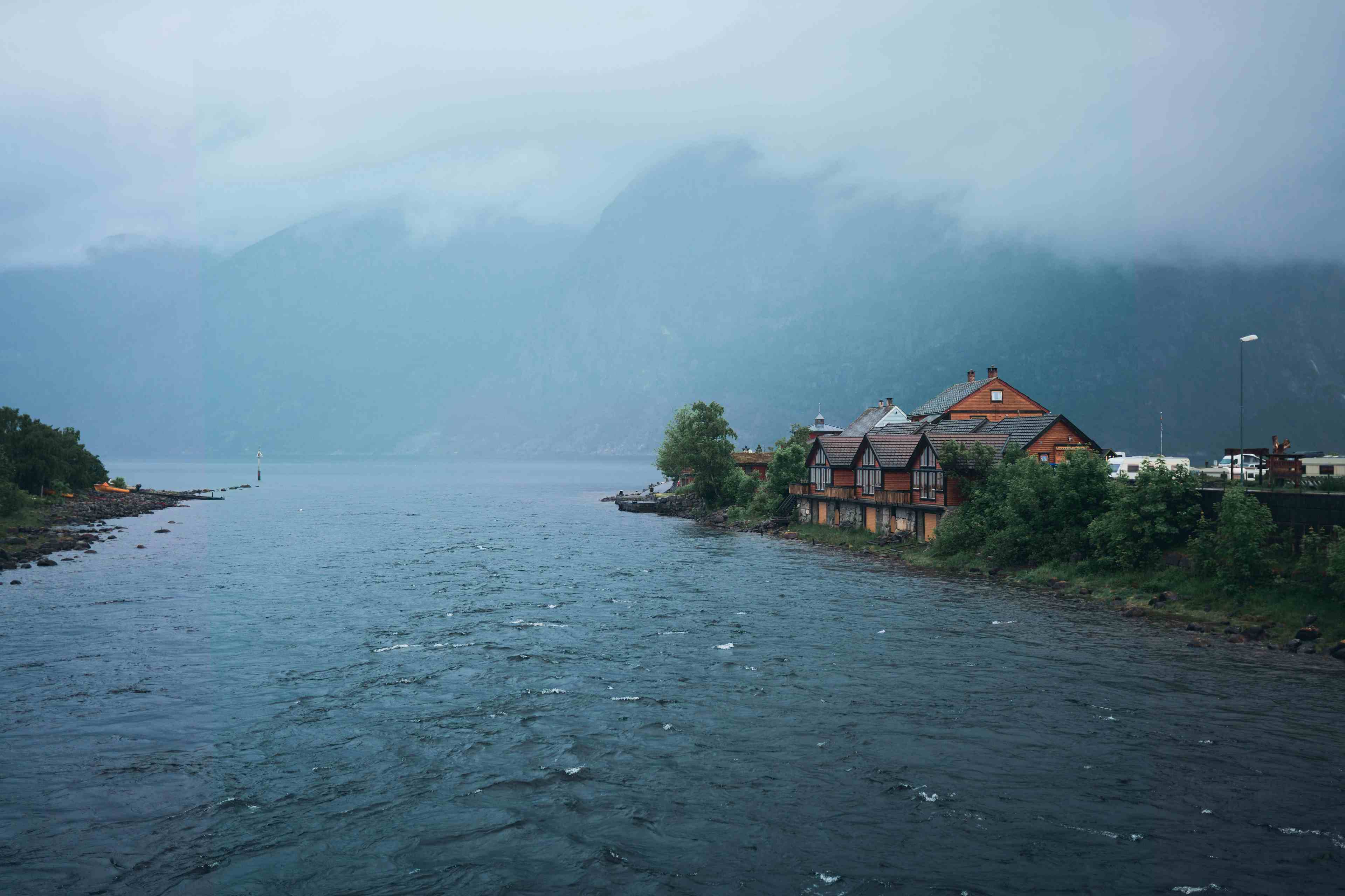 En oversikt over campingplassen som ligger langs en elv og ved siden av en fjord.