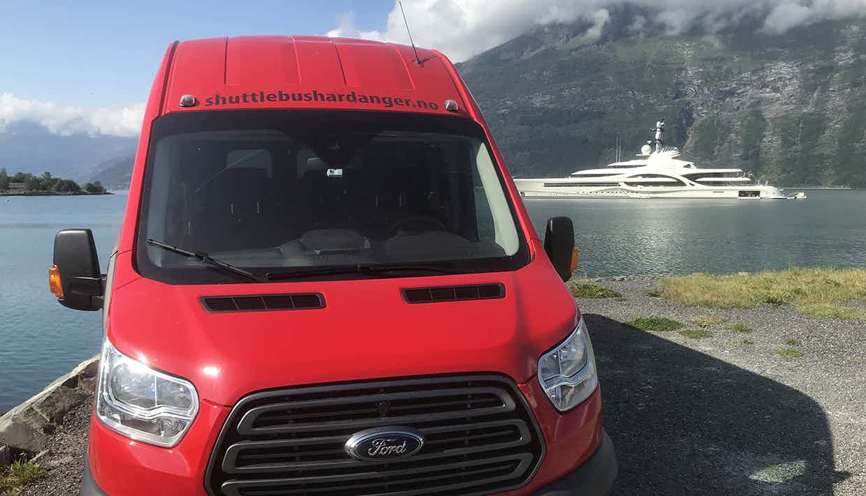 Shuttlebus med Hardangerfjorden i bakgrunnen.