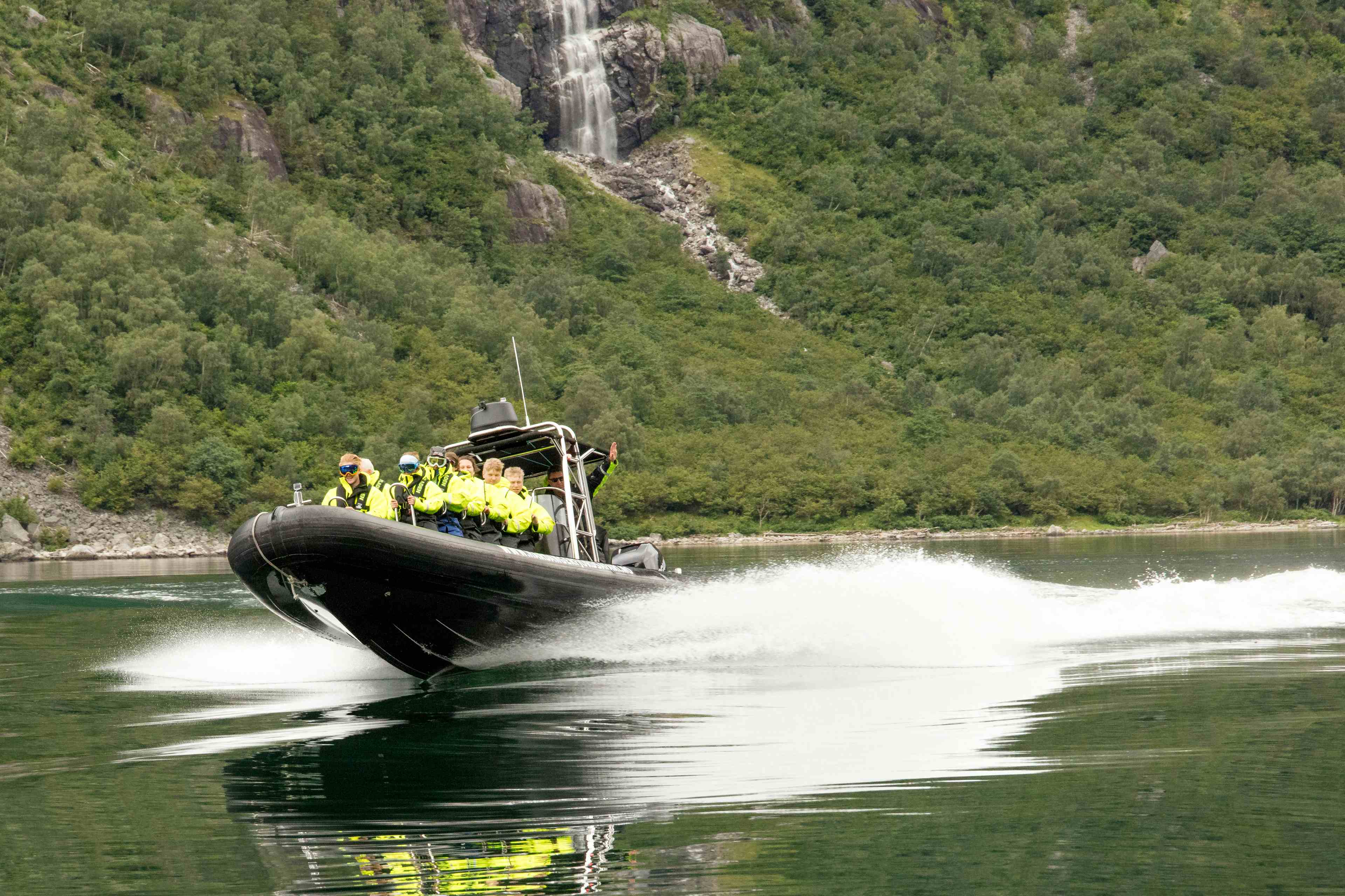 En ribbåt på fjorden, fylt med passasjerer.