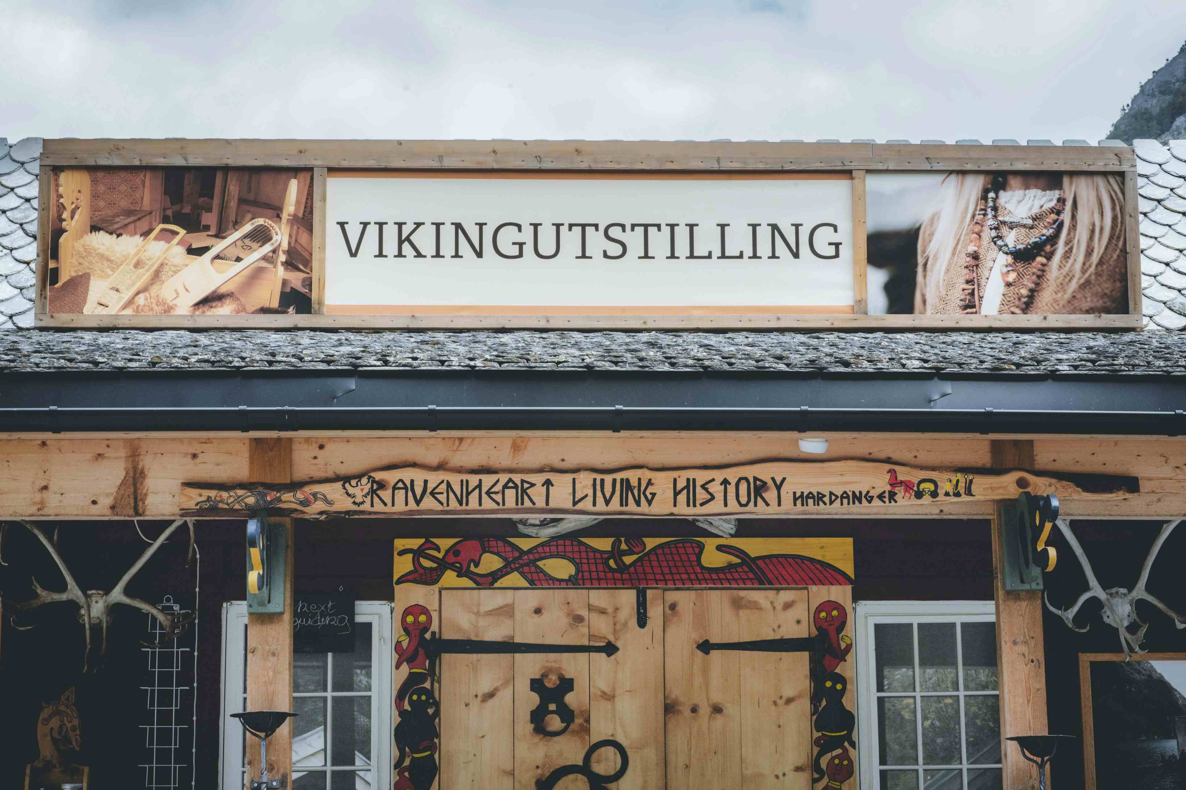 En kvinne utkledd som en viking, som står ved fjorden og spiller en vikingtromme.
