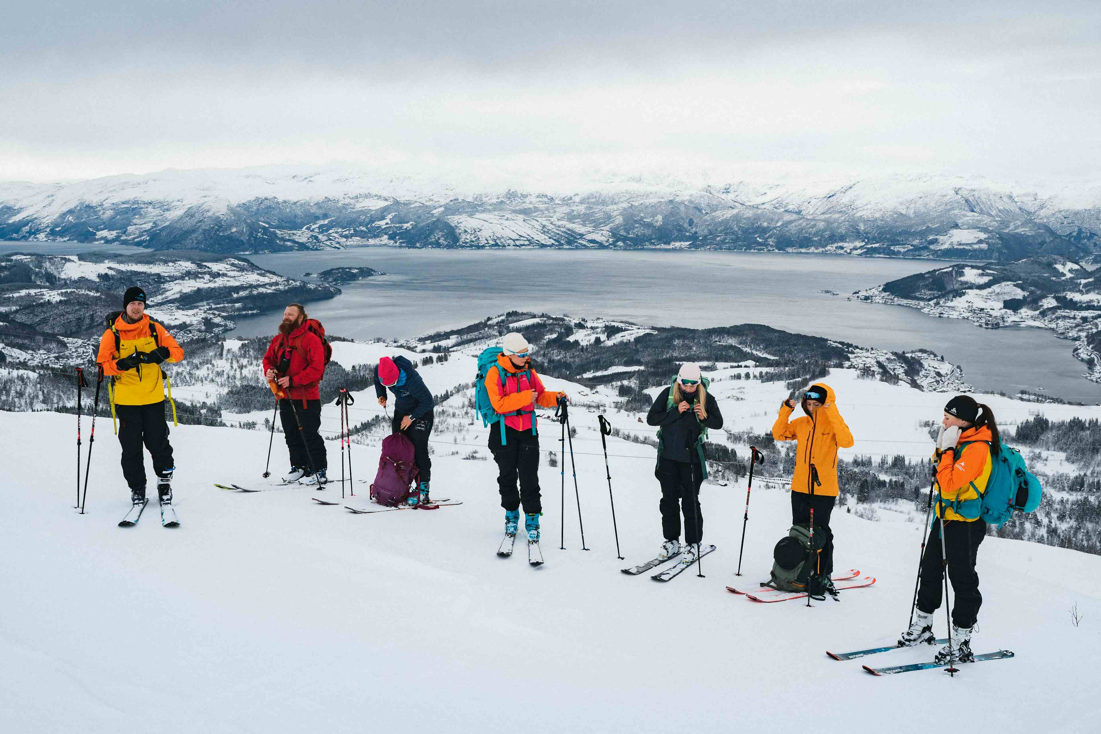 Topptur i Hardanger. Skikjører hopper ned en fjellside med utsikt mot Hardangerfjorden og snødekket landskap.
