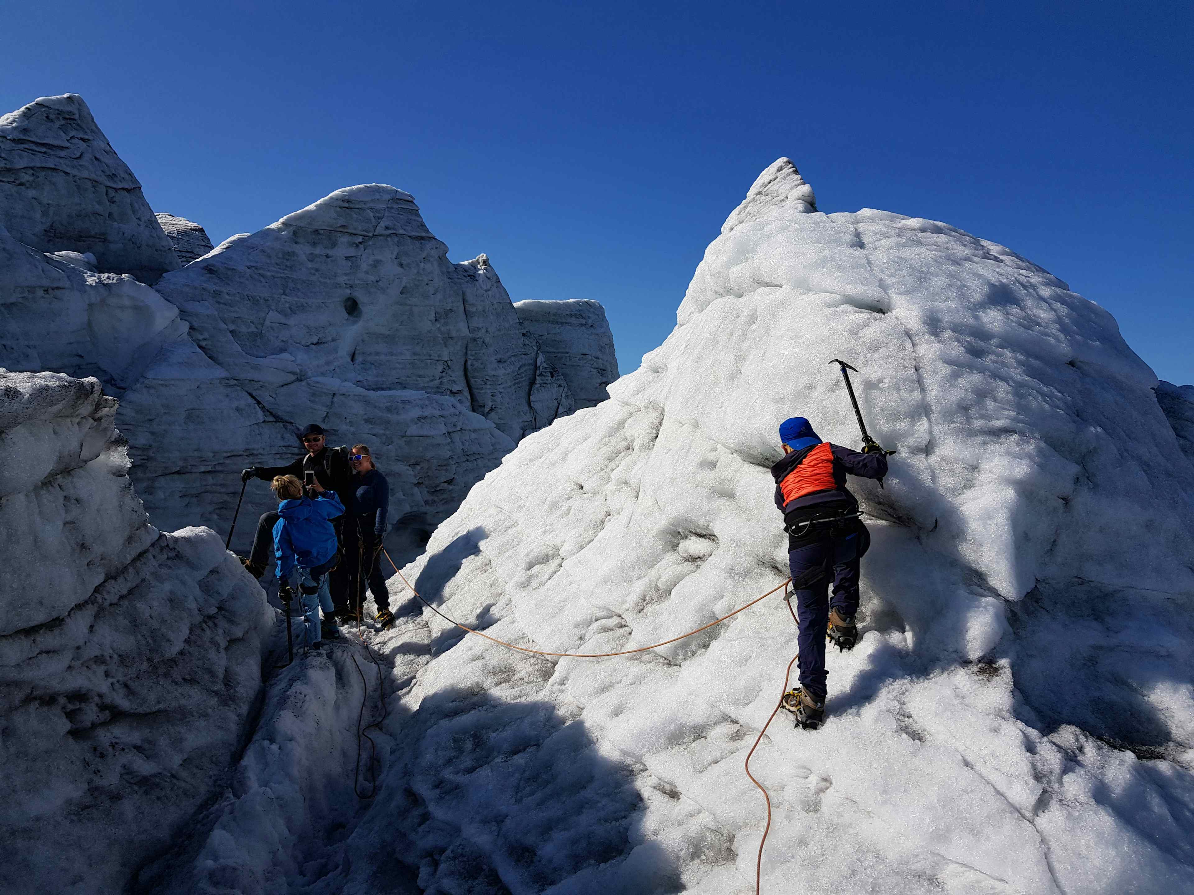 Folk går på isbre med blå himmel og guide i Hardanger