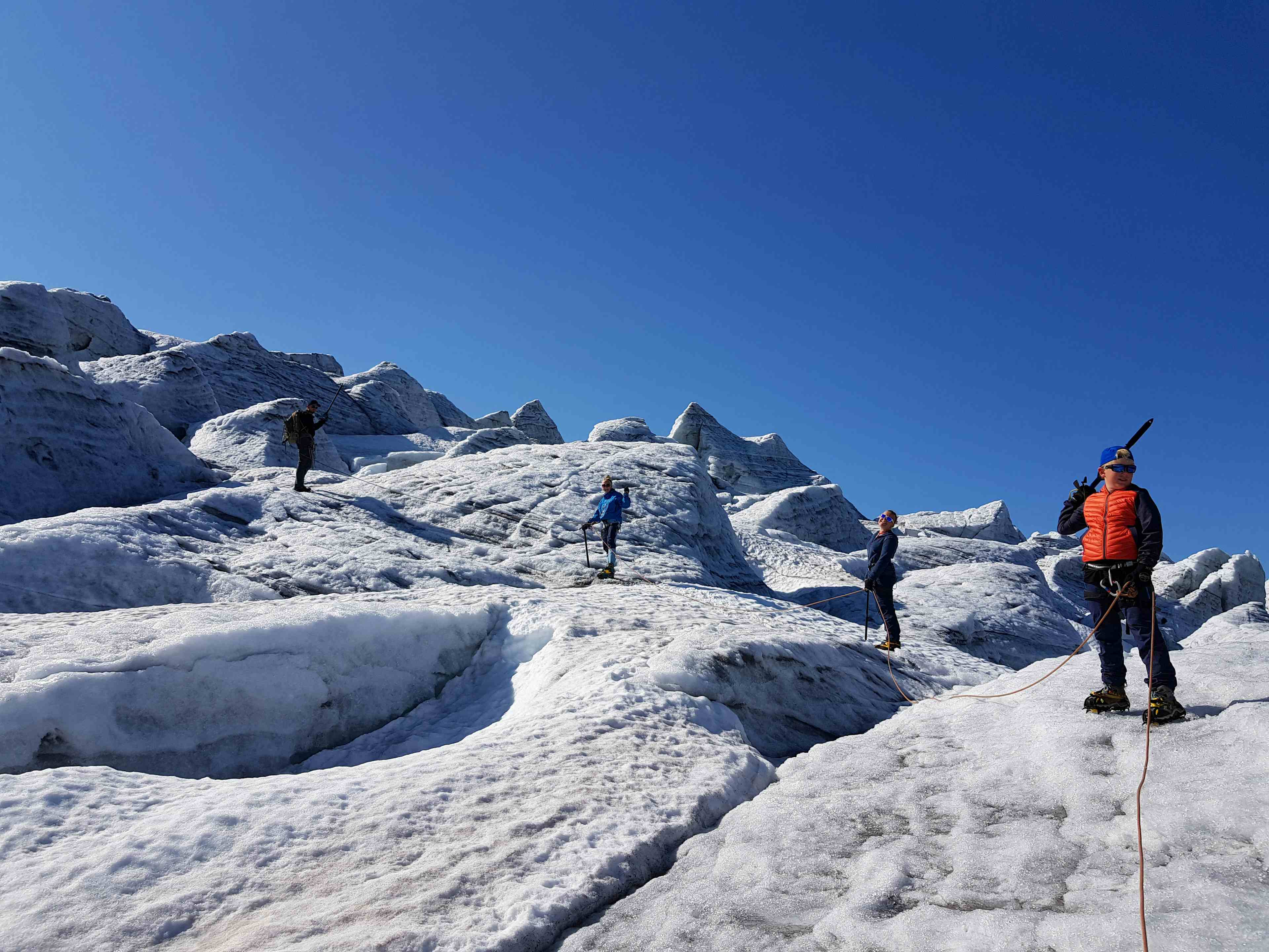 Folk går på isbre med blå himmel og guide i Hardanger